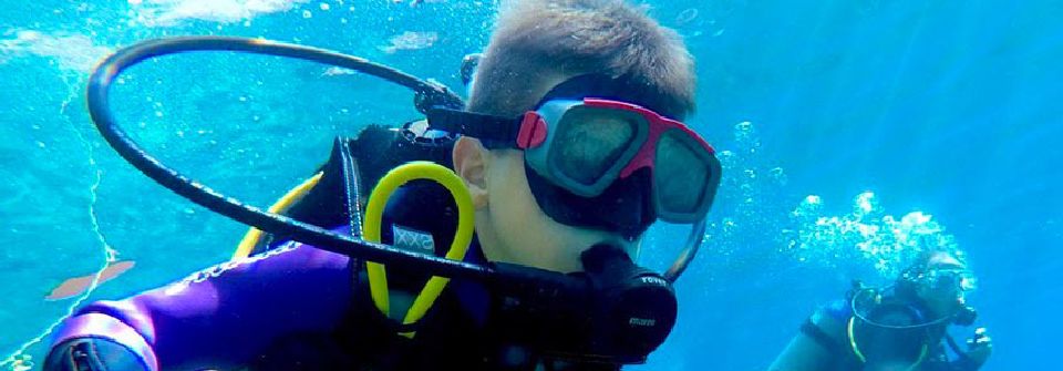 Instructor pointing out marine life to a student underwater.